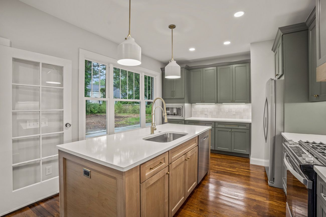 Sage green kitchen with white oak island and brass fittings