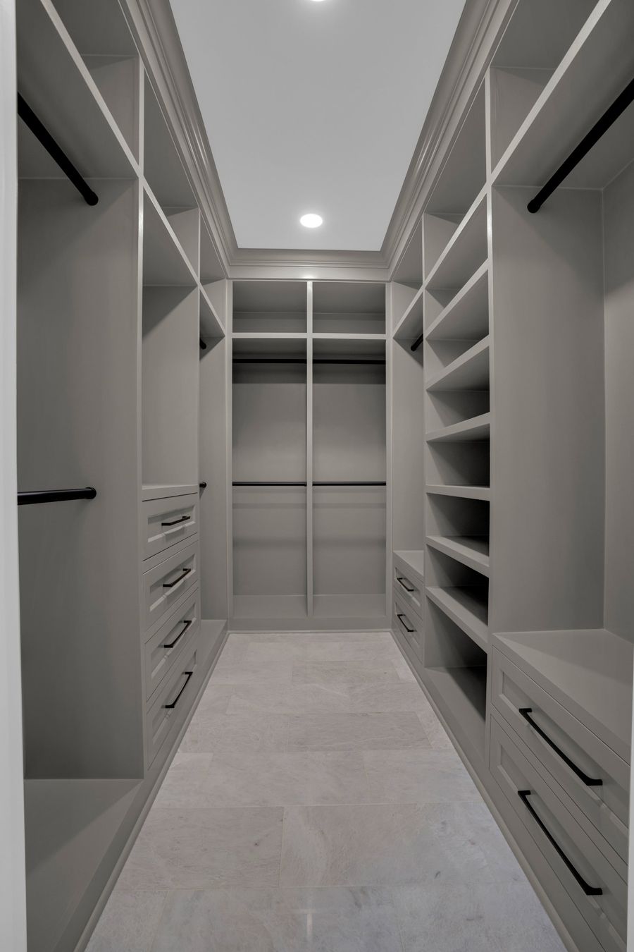 Finished closet with fitted cabinetry and stone floor