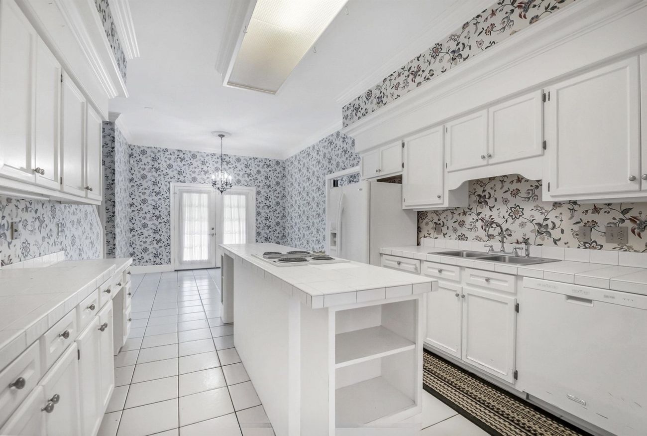 Closed galley kitchen with floral wallpaper and tile countertops