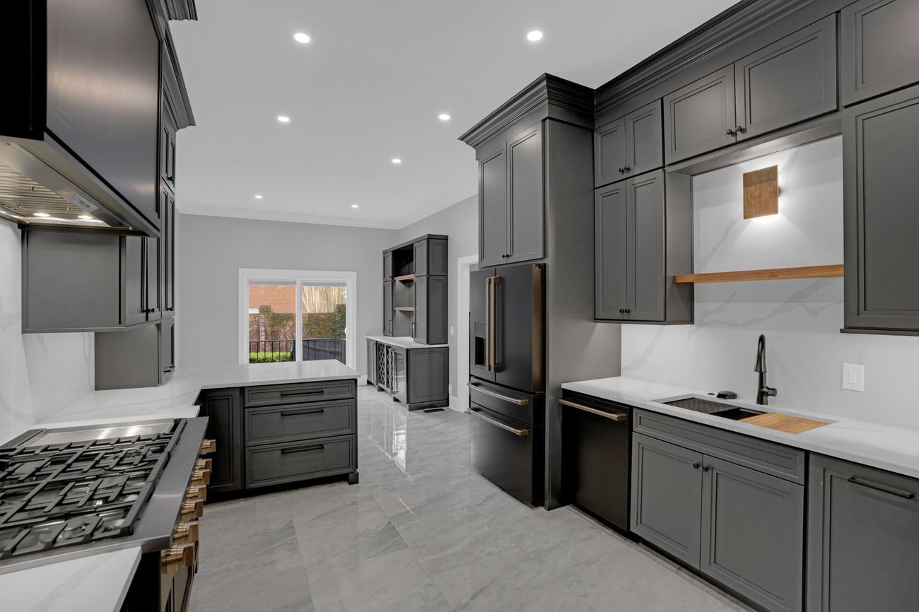 Finished kitchen in charcoal cabinetry with marble-look porcelain floor