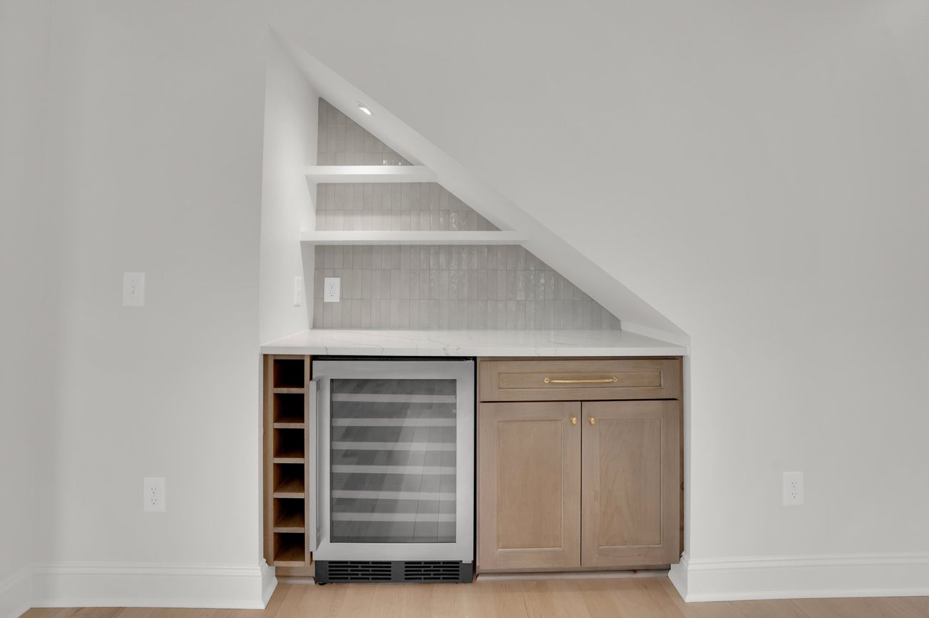 Bar built into the triangular space beneath the stair, with wine storage and tiled shelving