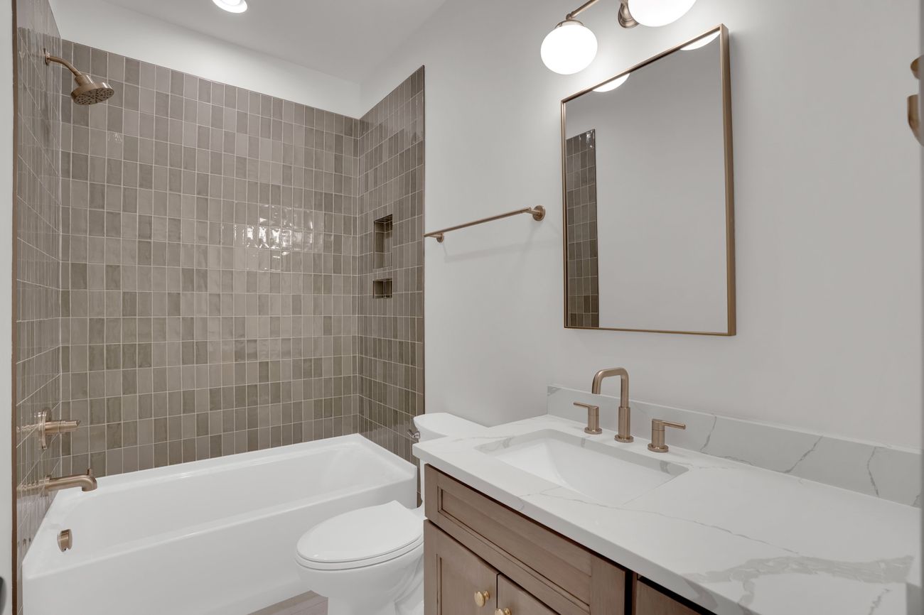 Secondary bath with stacked greige tile and brass fittings