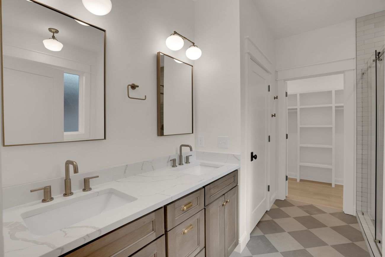 Primary bath with double vanity, brass fittings and a checkerboard floor