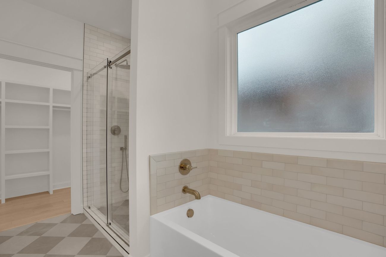 Primary bath looking toward the tub and shower, with the closet beyond