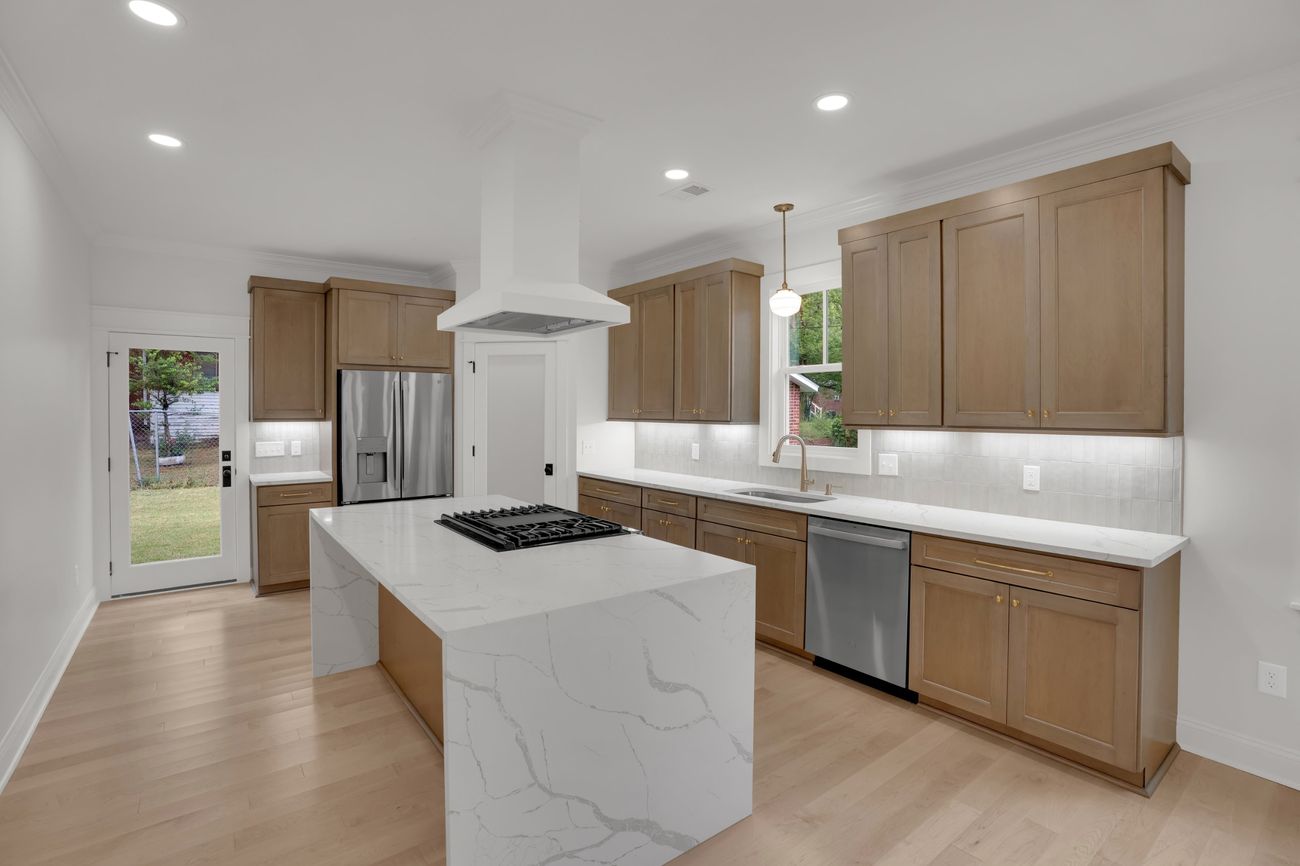 Finished kitchen with natural wood cabinetry and waterfall quartz island