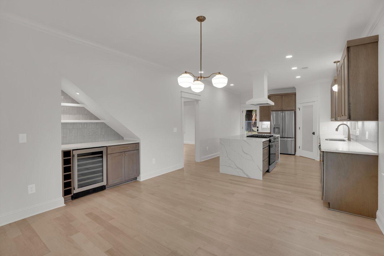 The same view built — kitchen and dining from the living room, stair bar at left