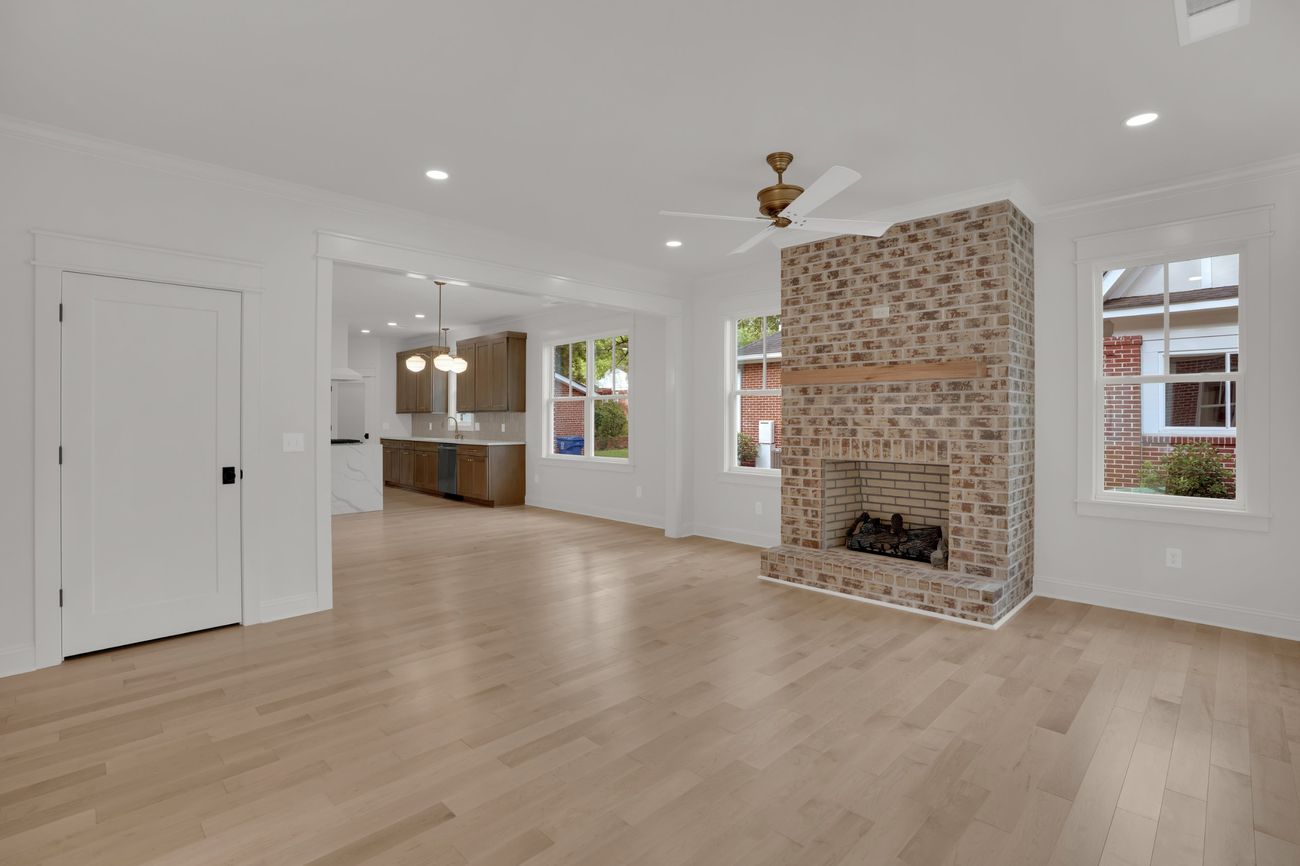 Living room with brick fireplace and a sightline through to the kitchen